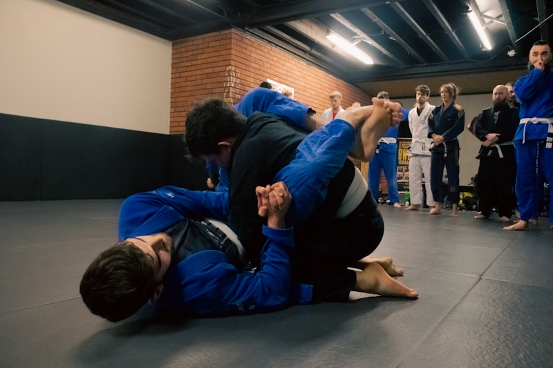 two men in blue and black suits are fighting in a gym