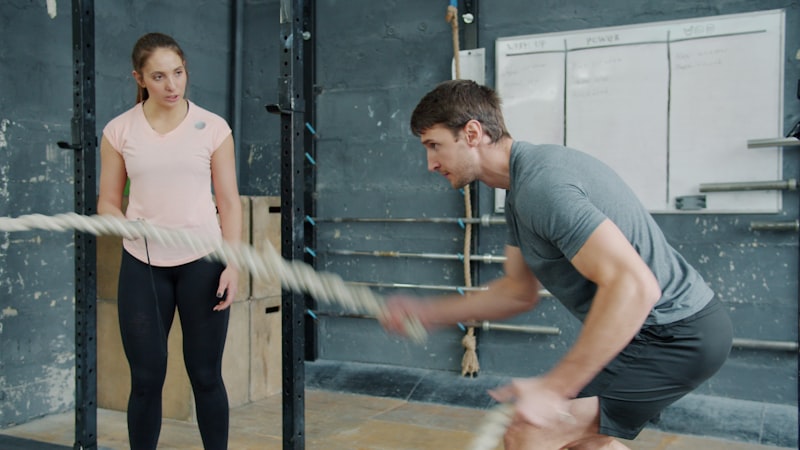 Man and woman exercising with battle ropes.
