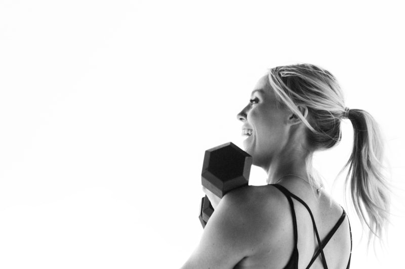 A woman with a ponytail holding a pair of dumbs