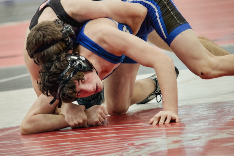 Two wrestlers grappling on a red mat