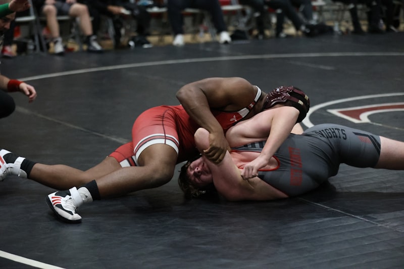 Two wrestlers grappling on a mat during a match