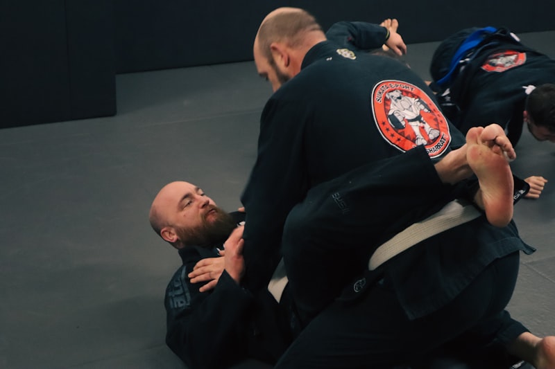 a man in a black jacket is doing a side control on another man in a