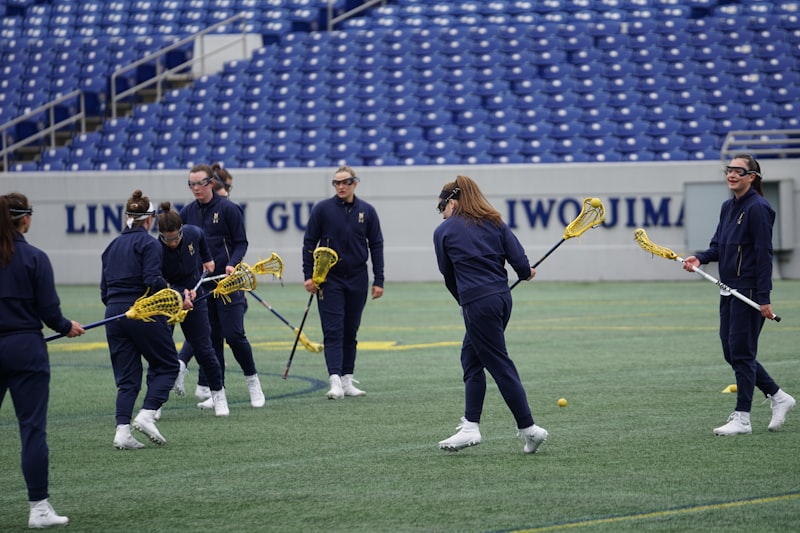 women playing lacrosse on field during daytime