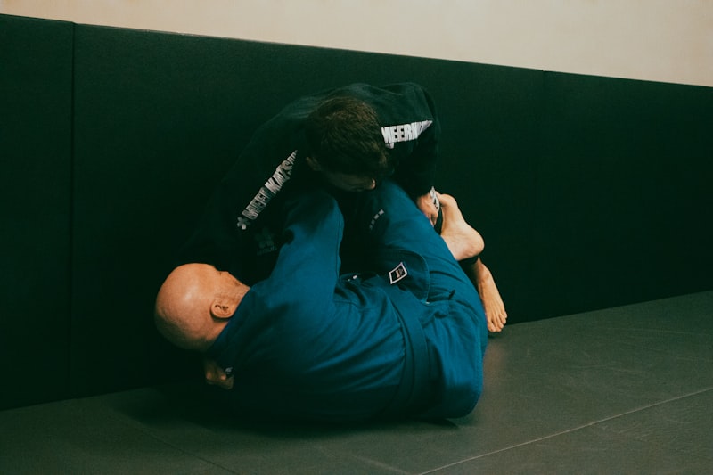 a man in a blue shirt is wrestling another man in a black shirt