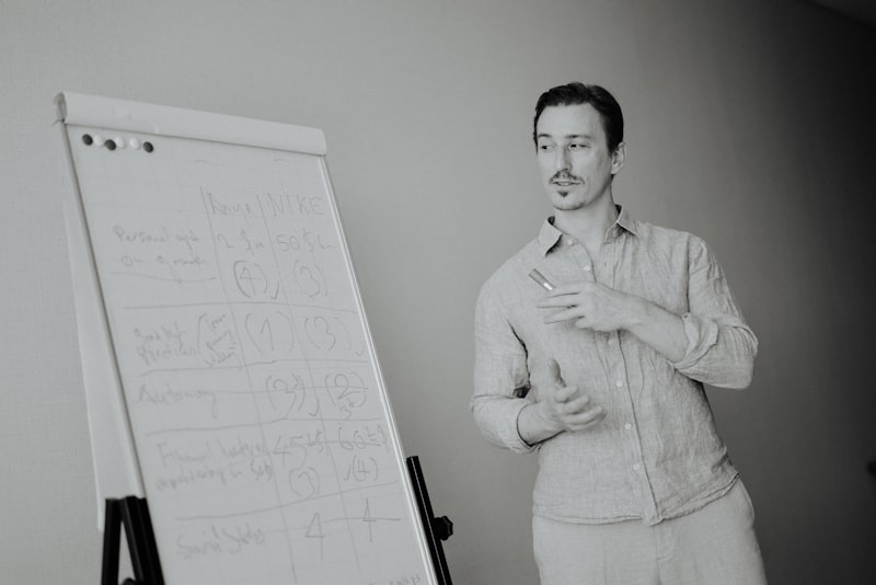 Man standing next to a whiteboard with writing.