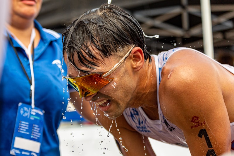 A man in a bathing suit splashing water on his face