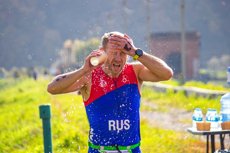 A man in a red, blue, and green shirt is drinking water from a