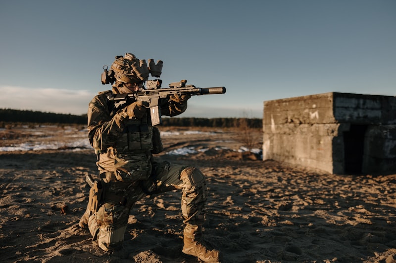 Soldier kneels and aims rifle in a training exercise.