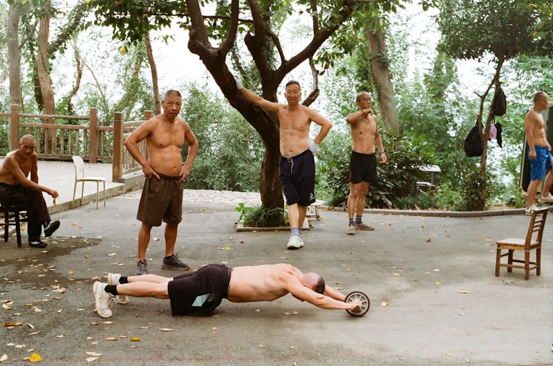 Men exercising outdoors with an ab roller wheel.