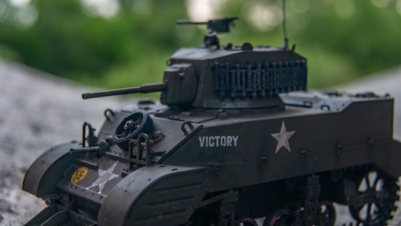 a toy army tank sitting on top of a road