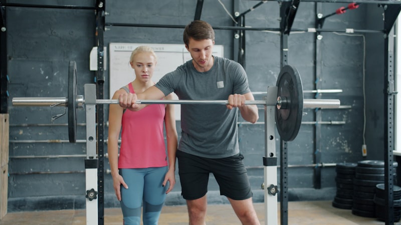 Man teaching woman weightlifting in gym