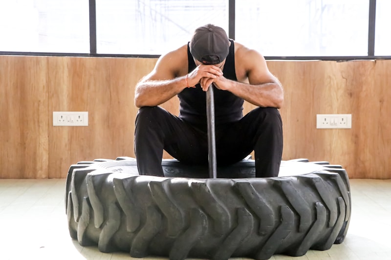 a man sitting on top of a large tire