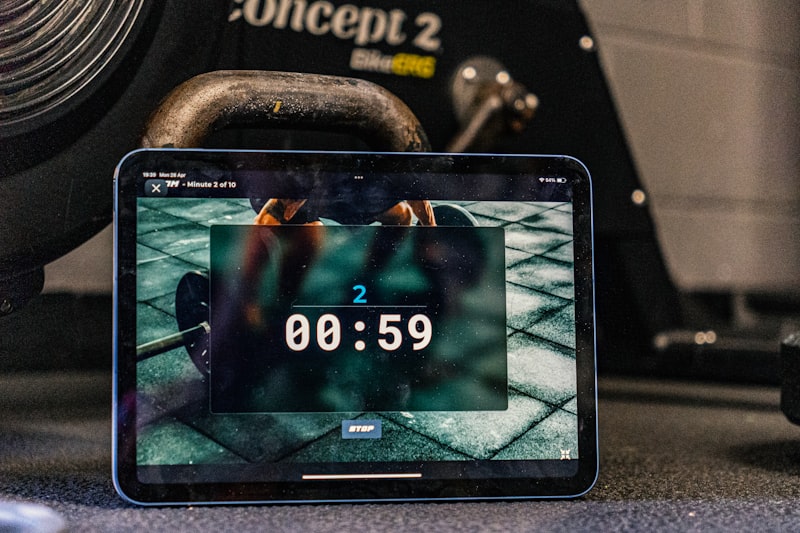 Tablet displays a timer, with workout equipment in background.