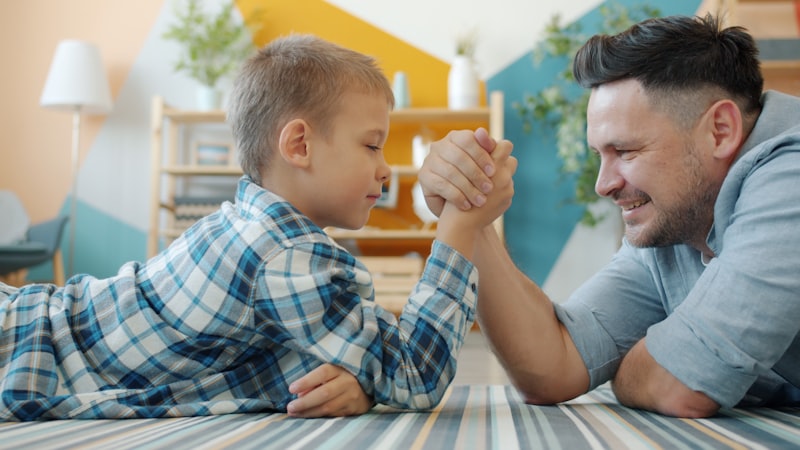Father and son arm wrestling on the floor.