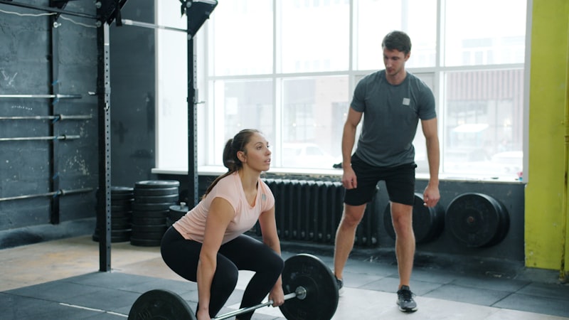 Woman lifting weights with trainer watching
