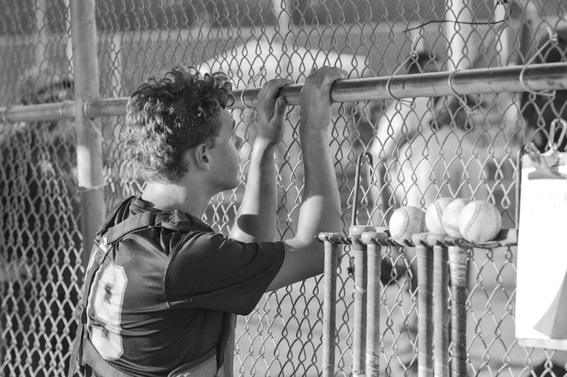 man in black t-shirt standing beside fence