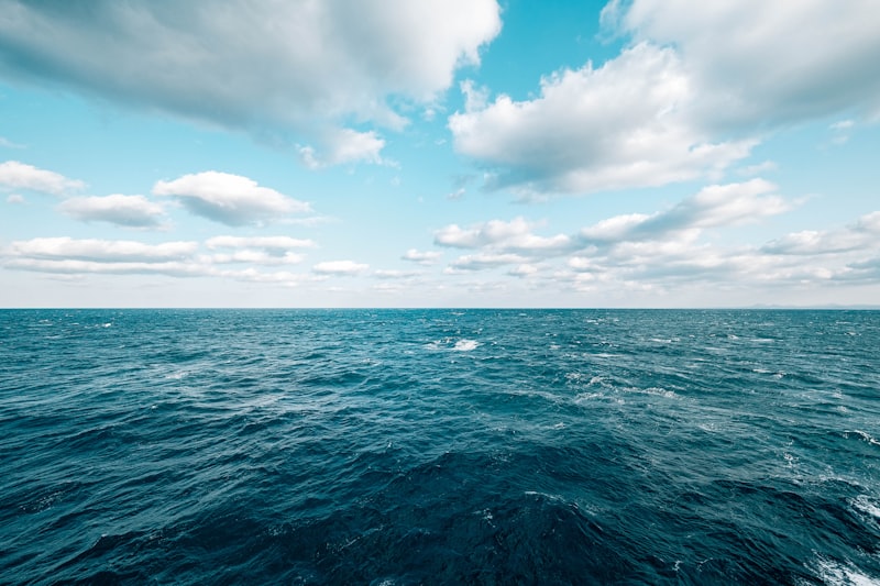 Ocean waves under a bright sky with clouds.