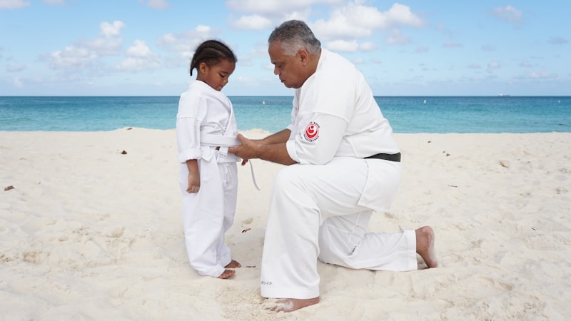 a man kneeling down next to a little girl on a beach